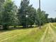 Green meadow alongside a dirt road and telephone pole on the property at 5410 A R Gordon Rd, Waxhaw, NC 28173