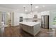 Bright kitchen features white cabinets, stainless steel appliances, a large island, and wood floors at 5590 Elk Knob Ct, Denver, NC 28037
