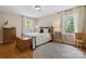 Bright bedroom featuring hardwood floors, two windows with white curtains, and a decorative area rug at 6745 Wheeler Dr, Charlotte, NC 28211