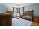 Cozy baby room featuring a wooden crib, glider, and patterned rug, and neutral tones at 6745 Wheeler Dr, Charlotte, NC 28211