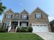 Charming two-story brick home with a well-manicured lawn, a two car garage, and a welcoming front porch at 707 Five Leaf Ln, Waxhaw, NC 28173