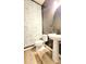 Stylish powder room with pedestal sink, decorative wallpaper accent wall, and wood-look tile flooring at 7170 Kenyon Dr, Denver, NC 28037