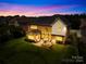 Stunning backyard view with a brick patio, outdoor seating, fire pit, and lush green lawn at twilight at 8460 Fairgreen Ave, Waxhaw, NC 28173