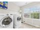 Convenient laundry room with modern washer and dryer, shelving, and a bright window at 8460 Fairgreen Ave, Waxhaw, NC 28173