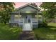 Charming home featuring a quaint porch, light gray siding, complemented by a well-maintained lawn and mature trees at 935 Church St, Kings Mountain, NC 28086
