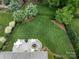 Aerial view of a meticulously landscaped backyard featuring a stone patio with a fire pit and lush greenery at 11324 Fullerton Place Nw Dr, Huntersville, NC 28078