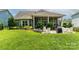Spacious backyard featuring a stone fire pit, outdoor dining set, covered patio, and lush lawn at 11324 Fullerton Place Nw Dr, Huntersville, NC 28078