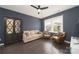 Living room featuring dark blue walls, a ceiling fan, and two leather chairs at 11324 Fullerton Place Nw Dr, Huntersville, NC 28078