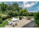 Beautiful patio with white chairs, a fire pit, and a grill, all surrounded by lush landscaping at 11324 Fullerton Place Nw Dr, Huntersville, NC 28078