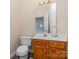 Compact half bathroom with pedestal sink, toilet, and wood-grain cabinets at 11802 Fox Glen Rd, Charlotte, NC 28269