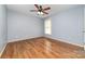 This bedroom offers natural light, a ceiling fan and neutral walls over wood floors at 11802 Fox Glen Rd, Charlotte, NC 28269