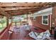 Spacious covered deck with stained wood flooring, outdoor furniture, ceiling fan, and red brick home exterior at 158 Jane Sowers Rd, Statesville, NC 28625