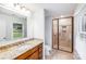 Well lit bathroom featuring granite counters, wood cabinets and tiled shower with glass door at 16512 Kimbolten Dr, Huntersville, NC 28078