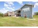 Features an outdoor fireplace, green lawn, gray siding, covered grill, walkout basement, and a screened in porch at 1663 Tranquility Blvd, Lancaster, SC 29720