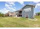 Features an outdoor fireplace, green lawn, gray siding, covered grill, walkout basement, and a screened in porch at 1663 Tranquility Blvd, Lancaster, SC 29720