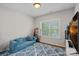 This cozy bedroom is brightly lit by a window overlooking the lush backyard and features a stylish blue sofa and patterned rug at 1849 Still Water Ln, Indian Land, SC 29707