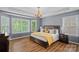 Comfortable main bedroom with a tray ceiling, chandelier, hardwood floors, and large windows at 1849 Still Water Ln, Indian Land, SC 29707