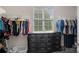 This large walk-in closet with a window features dual rods for hanging clothes and a stylish dark dresser at 1849 Still Water Ln, Indian Land, SC 29707