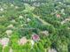 Aerial view of home with a pool, surrounded by lush trees, near a golf course at 1868 Chestnut Hill Dr, Tega Cay, SC 29708