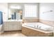 Relaxing primary bathroom features a large soaking tub, tiled walls, and a white double sink vanity at 1868 Chestnut Hill Dr, Tega Cay, SC 29708