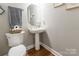 Cozy powder room with a pedestal sink, wooden floors, and neutral wall color at 1868 Chestnut Hill Dr, Tega Cay, SC 29708