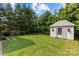 Landscaped backyard featuring a shed, lush green grass, trees, and a brick fence at 206 Hillside Ave, Charlotte, NC 28209