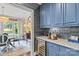 This butler pantry features blue cabinetry, wine fridge, marble countertop, and access to dining room at 206 Hillside Ave, Charlotte, NC 28209