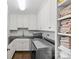 Well-lit laundry room with white cabinets, dark countertops, a sink, stainless steel washer/dryer, and linen storage at 206 Hillside Ave, Charlotte, NC 28209