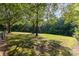 Spacious backyard featuring mature trees, lush green grass, and a walking trail, perfect for outdoor activities at 214 Silver Creek Ln, Shelby, NC 28152