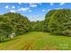 Lush backyard with plenty of green space and mature trees providing a private, park-like setting for outdoor activities at 296 Hicks Creek Rd, Troutman, NC 28166