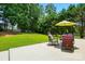 Enjoy the outdoors on the patio in this expansive backyard with mature trees and lush lawn at 3005 Streamlet Way, Monroe, NC 28110