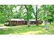 Serene exterior view of a brick home nestled among mature trees and lush greenery at 3158 Salisbury Hwy, Statesville, NC 28677