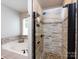 Bathroom featuring a soaking tub and glass-enclosed shower with tile and stone accents at 3347 Xandra Ct, Indian Land, SC 29707