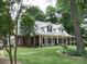Charming single-Gathering home featuring a manicured lawn, dormer windows, and a welcoming front porch with rocking chairs at 390 Robinson Rd, Mooresville, NC 28117