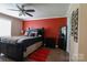 Comfortable bedroom with a ceiling fan, dark furniture, red accent wall, and wood-look floors at 400 Majolica Rd, Salisbury, NC 28147