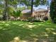 Spacious backyard featuring a green lawn, bordered by trees and a brick house at 4026 Sharon View Rd, Charlotte, NC 28226