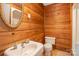 Bathroom features wood paneling, sink, toilet, mirror, and overhead shower at 417 Phifer Rd, Kings Mountain, NC 28086