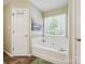 Bright bathroom with a soaking tub under a sunny window and decorative art at 7300 Bailywick Dr, Waxhaw, NC 28173