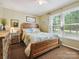 Cozy bedroom with a wooden bed frame, bedside table, and sunlit window at 7300 Bailywick Dr, Waxhaw, NC 28173
