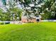 Expansive backyard with well-kept lawn, patio area, and recreational equipment under mature trees at 734 Forestbrook Dr, Gastonia, NC 28056