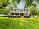 Classic two-story home with a welcoming brick porch and mature trees in a green lawn at 734 Forestbrook Dr, Gastonia, NC 28056