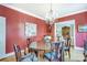 Formal dining room with red walls, chandelier, hardwood floors, and elegant decor with a view to the living room at 1021 Isleworth Ave, Charlotte, NC 28203