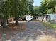 Camper on a gravel lot, surrounded by trees, a shed, and a screened-in porch at 103 Powder Horn Trl, Mount Gilead, NC 27306