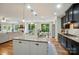 Modern kitchen with dark cabinets, granite counters, stainless appliances, and island with seating and view to living room at 110 St Sophia Ct, Mooresville, NC 28117