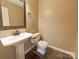 Well-lit half-bath with pedestal sink, tile flooring, and decorative mirror at 12092 Spinnaker Dr, Fort Mill, SC 29708