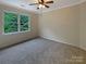 Bright, carpeted bedroom with a ceiling fan and tree views from a large window at 12092 Spinnaker Dr, Fort Mill, SC 29708