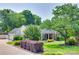 Charming home with a brick facade, manicured lawn, mature trees, and a paved driveway leading to a two-car garage at 12311 Bentcreek Ln, Matthews, NC 28105