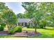 Traditional brick home featuring a manicured lawn, mature trees, and a welcoming front porch and landscaping at 12311 Bentcreek Ln, Matthews, NC 28105
