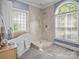Bright bathroom featuring a modern tub, glass block window and a tiled walk-in shower with large neutral colored tiles at 150 Pinnacle Shores Dr, Mooresville, NC 28117
