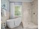 Bright bathroom featuring a modern tub, glass block window and a tiled walk-in shower with large neutral colored tiles at 150 Pinnacle Shores Dr, Mooresville, NC 28117